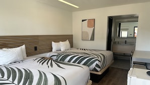 Une chambre d’hôtel avec deux lits, une tête de lit en bois, un tableau au mur et un bureau avec une chaise.