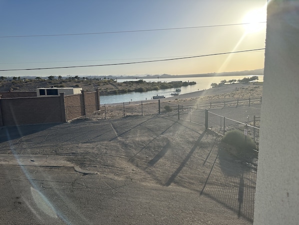 A view of a parking area with a river and boats in the background.
