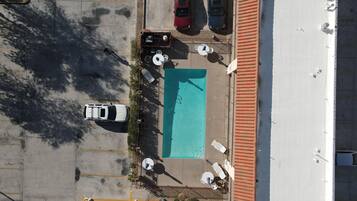 An aerial view of a parking lot with a swimming pool, two cars, and outdoor seating.