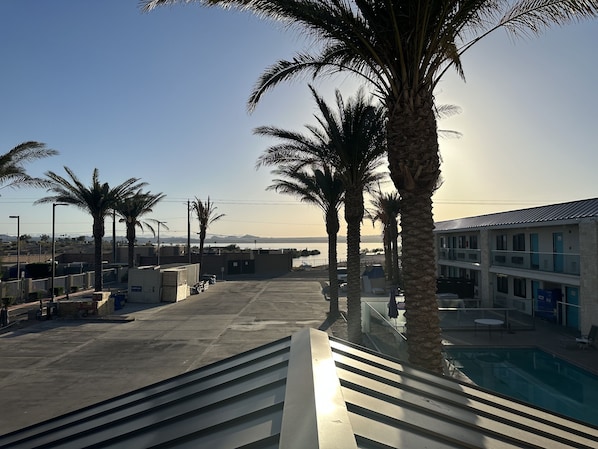 A pool area with palm trees, a clear sky, and a view of distant mountains.