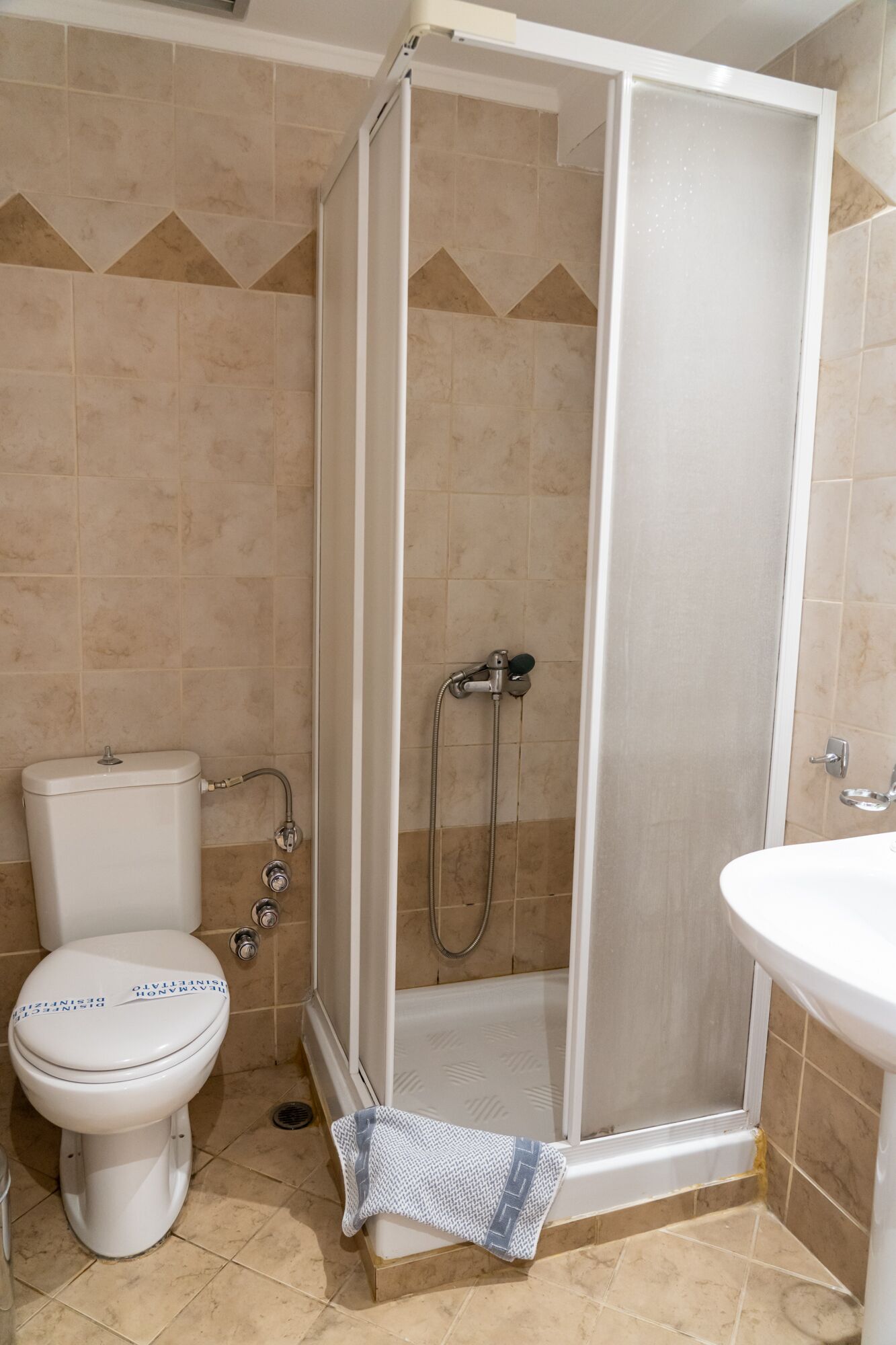 A bathroom with a toilet, a shower enclosure, and a sink.