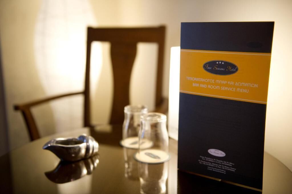 A hotel room with a dining table set for two, a menu stand, and a decorative silver bowl.