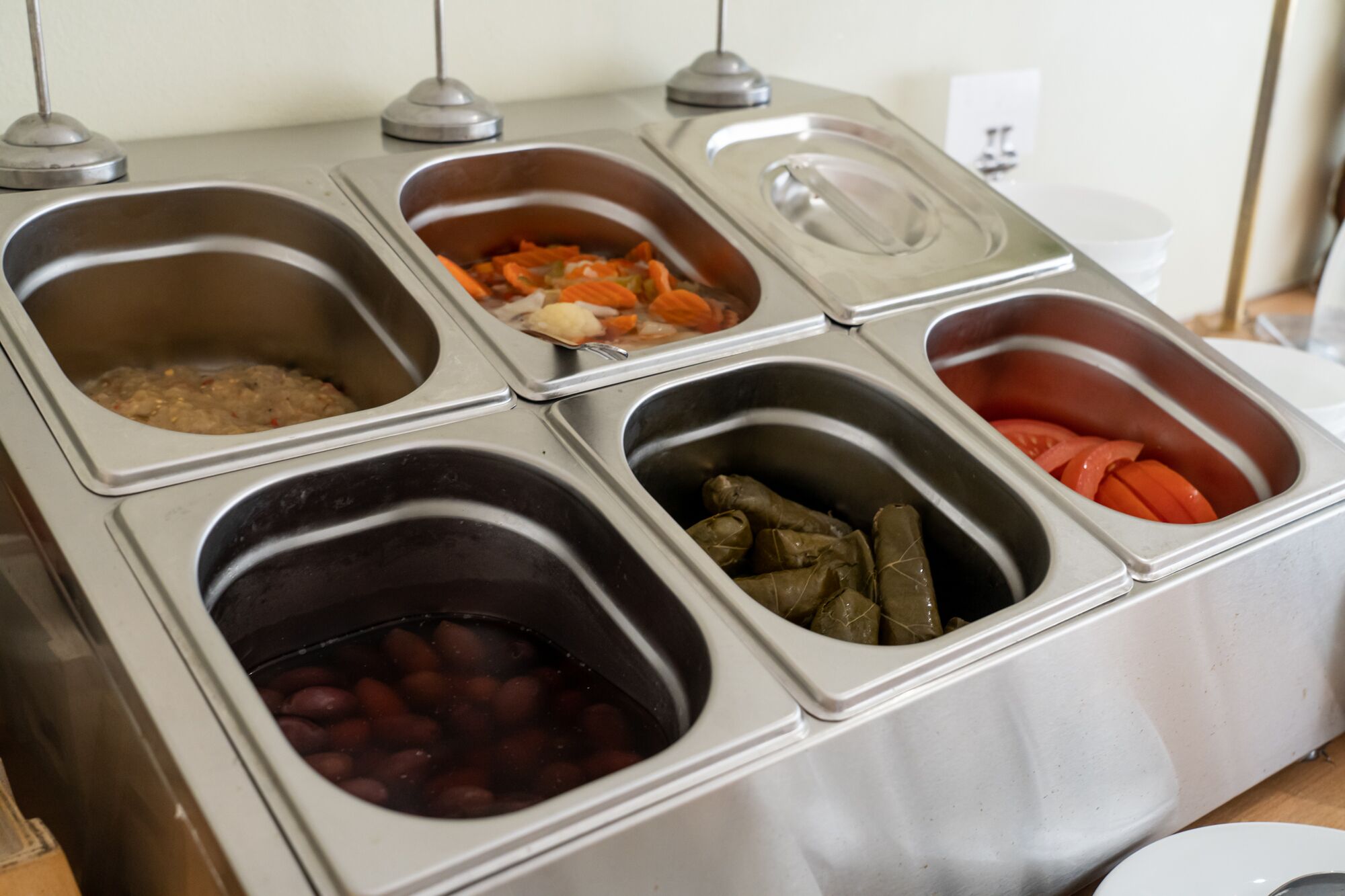 Un bufé con diversas opciones de comida, incluyendo frijoles, verduras y un plato de carne.