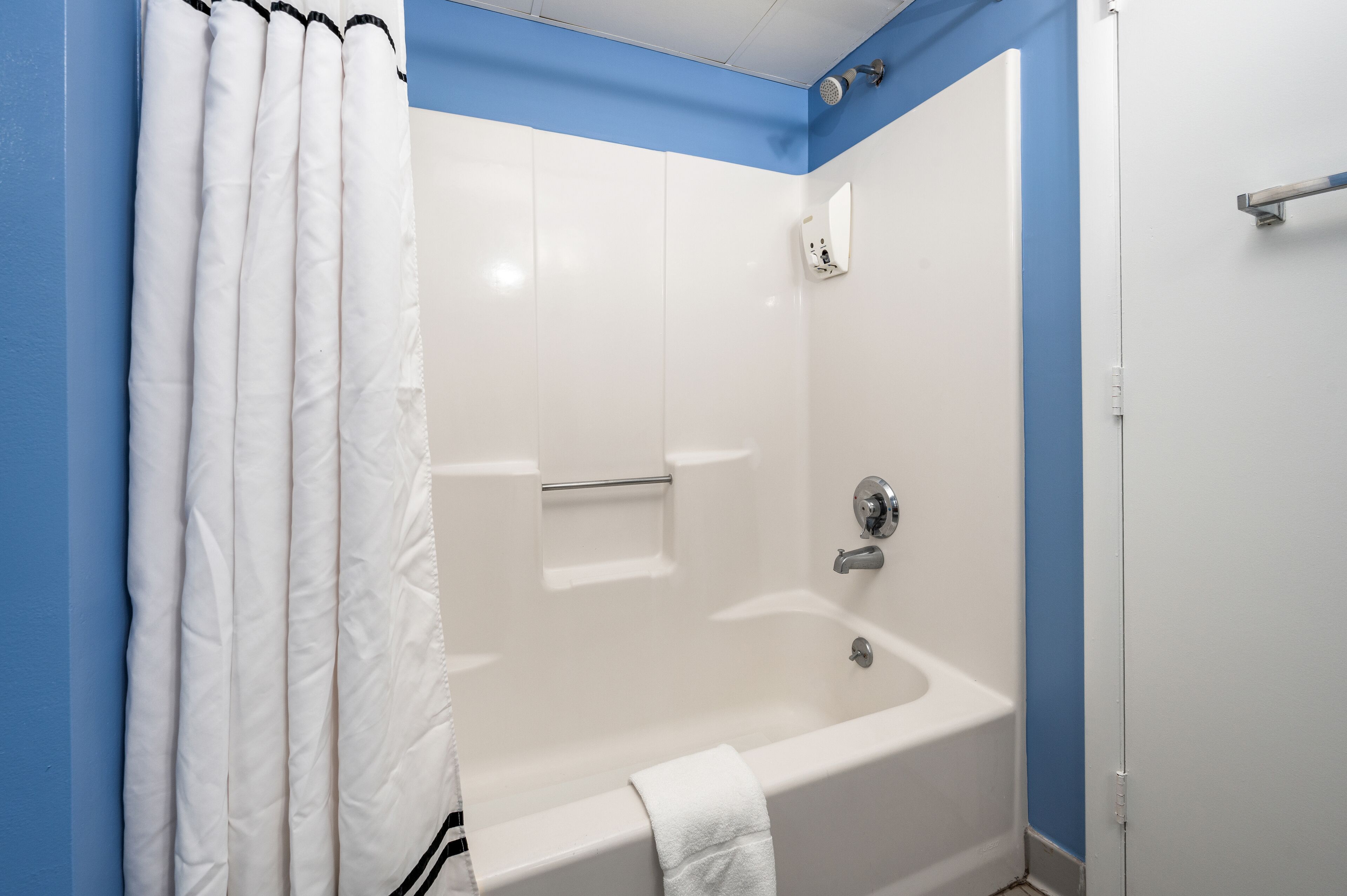 Un baño con una bañera blanca, zona de ducha y un perchero para toallas.