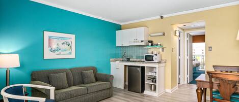 A compact living space with a kitchenette, a sofa, a dining table, and a chair.