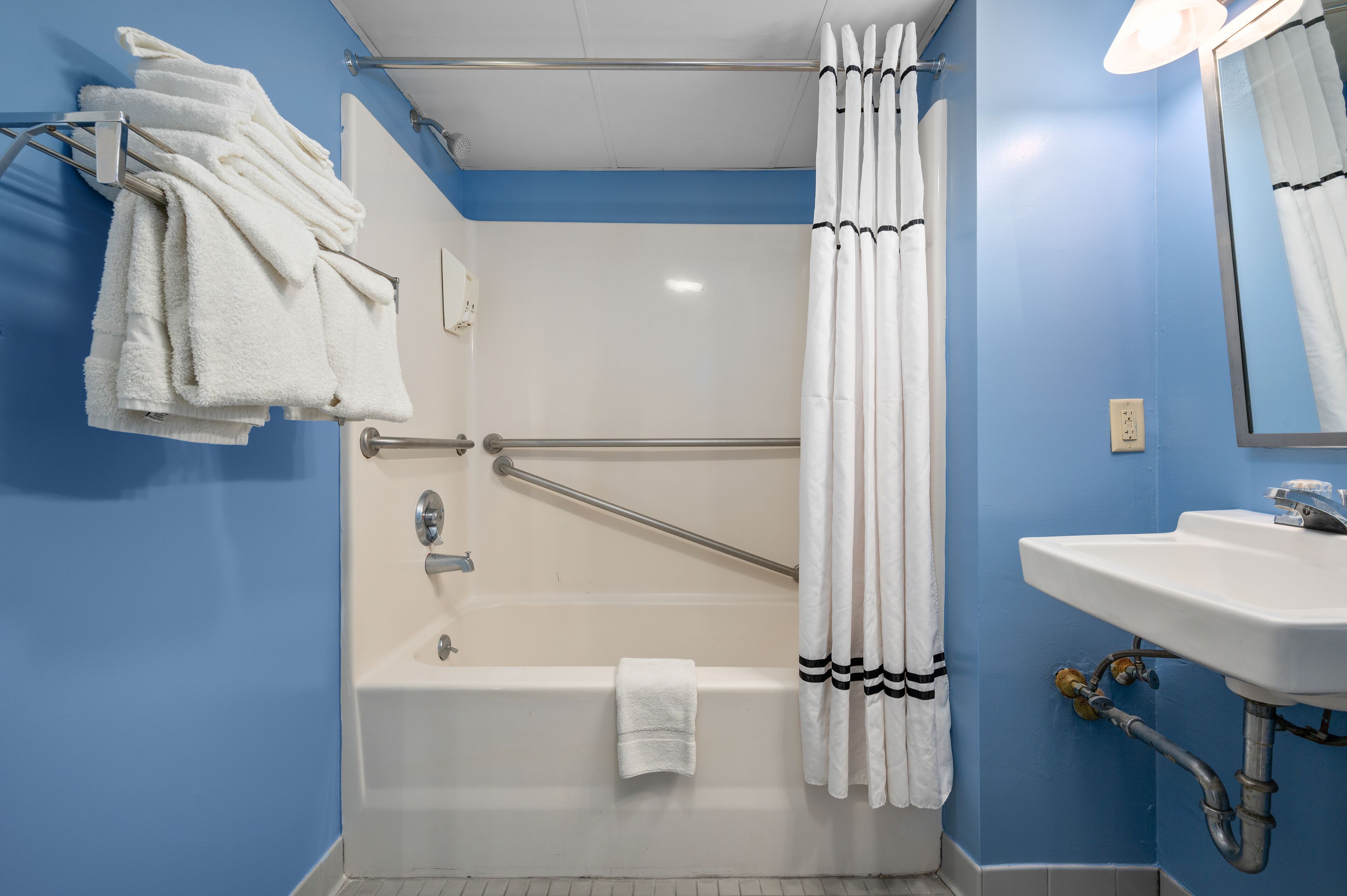 Een badkamer met een bad, een wit wastafel en een douchegordijn.
