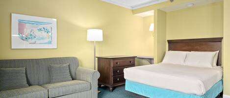 Ein Hotelzimmer mit Bett, Sofa, Nachttisch und Lampe.