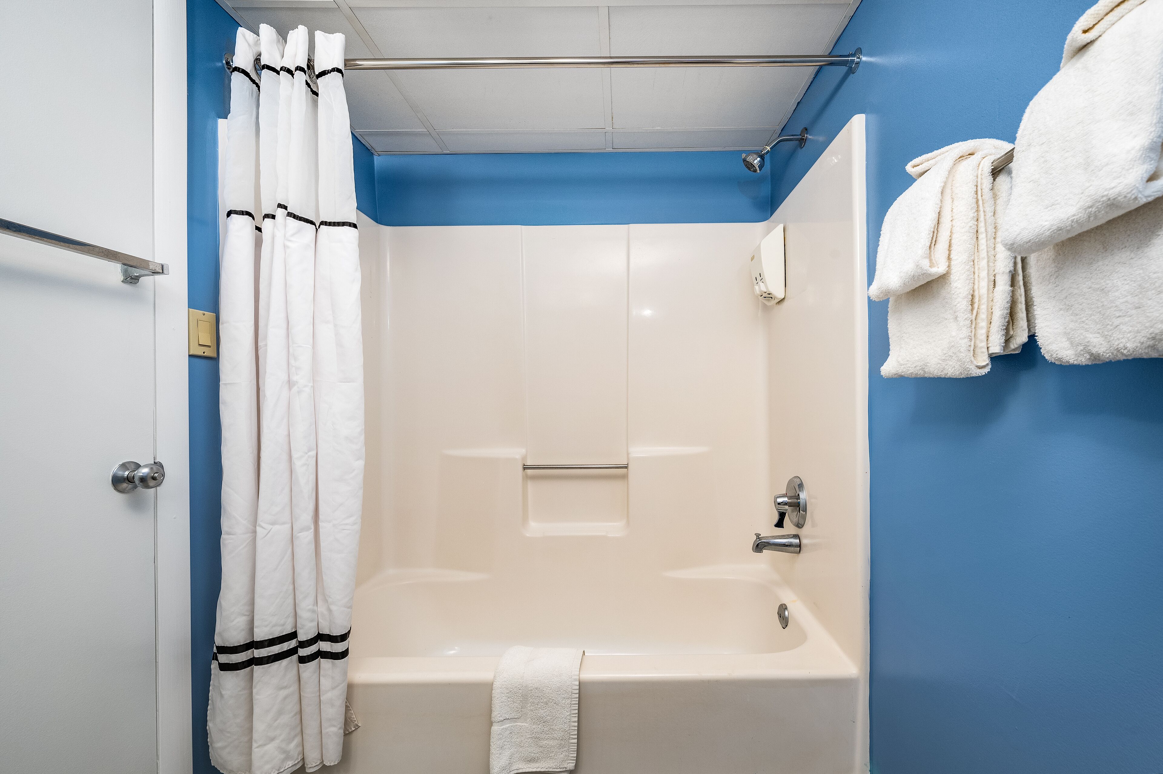 A bathroom with a bathtub, a shower curtain, and towels on a rack.
