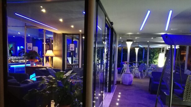 A modern hotel lobby with a bar area, seating, and a visible entrance. - Hotel Blue Rose's (Mesagne)