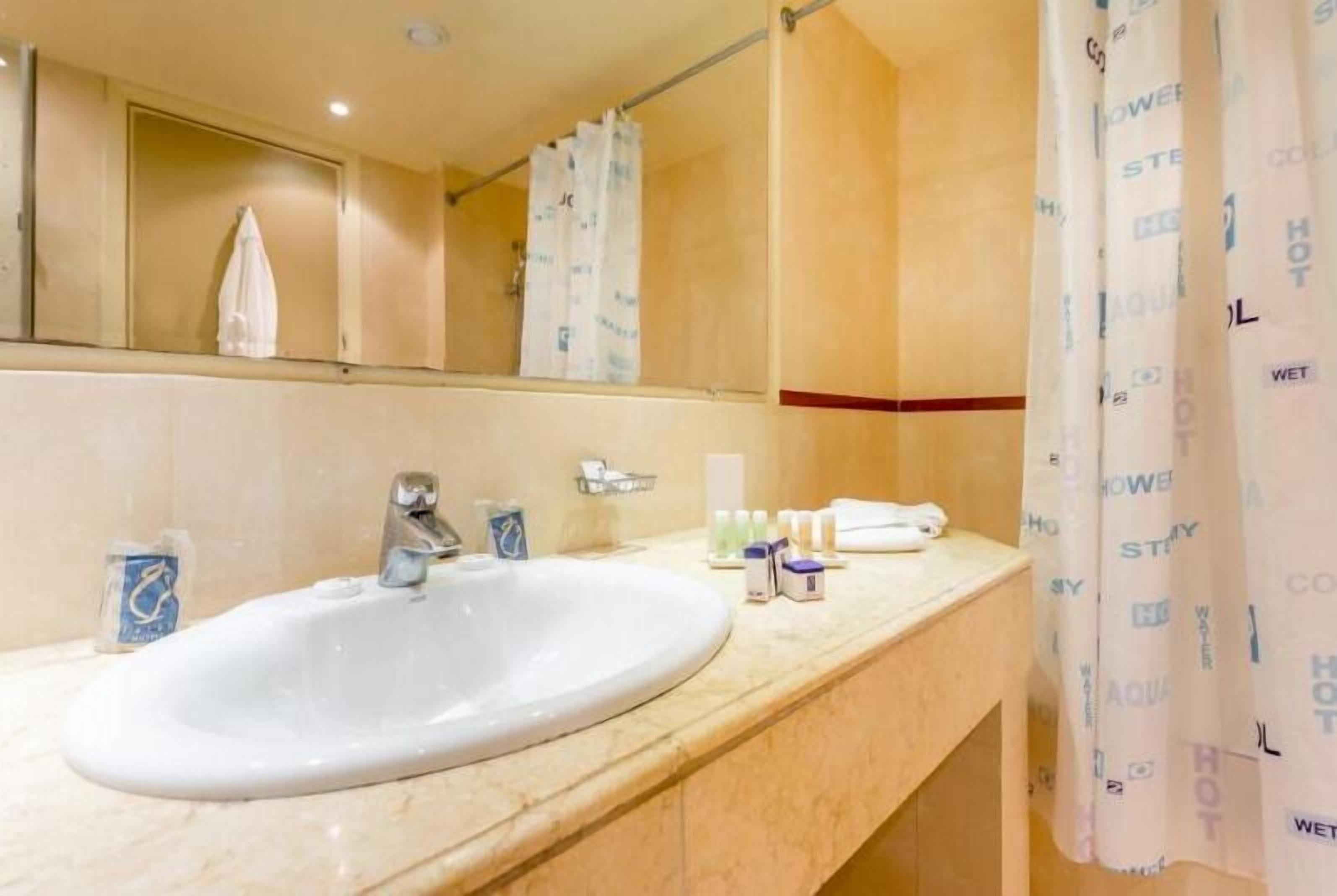A bathroom with a sink, mirror, and shower curtain.