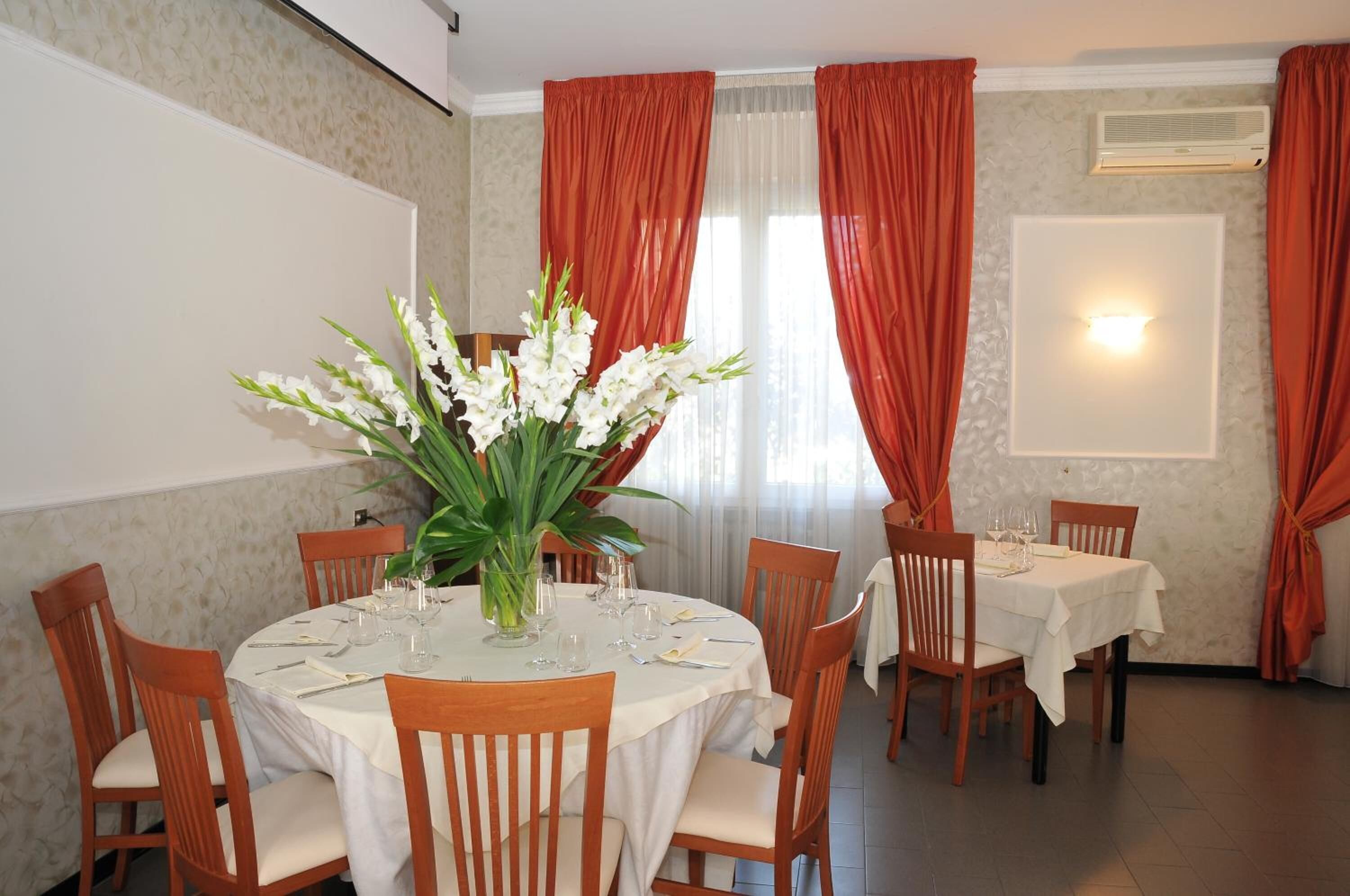 Un espace repas avec des tables rondes, des chaises en bois et un grand arrangement floral au centre.