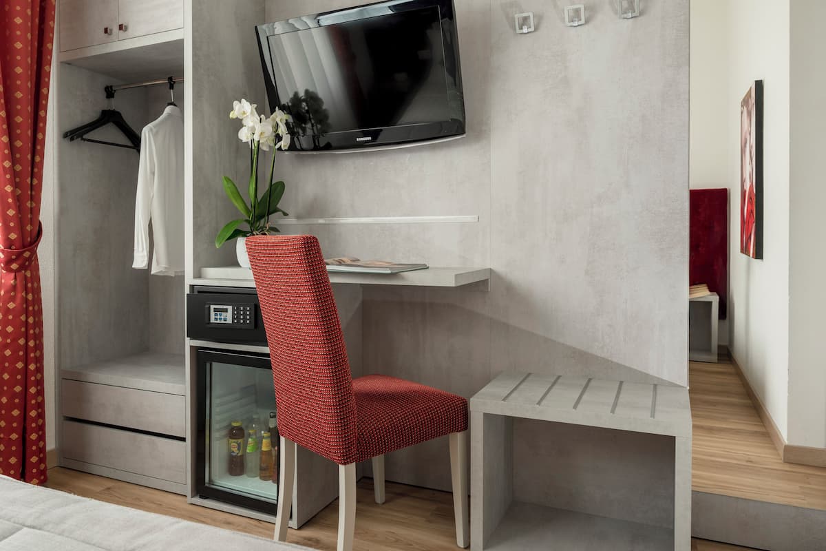 A modern hotel room with a TV, a desk, a chair, and a wardrobe.