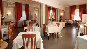 A restaurant with multiple tables and chairs, red curtains, and a well-lit interior. - Hotel Mini Palace Country House (Molinella)