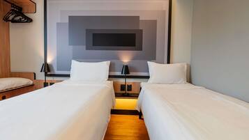A hotel room with two beds, a large wall art piece, and a wooden headboard.