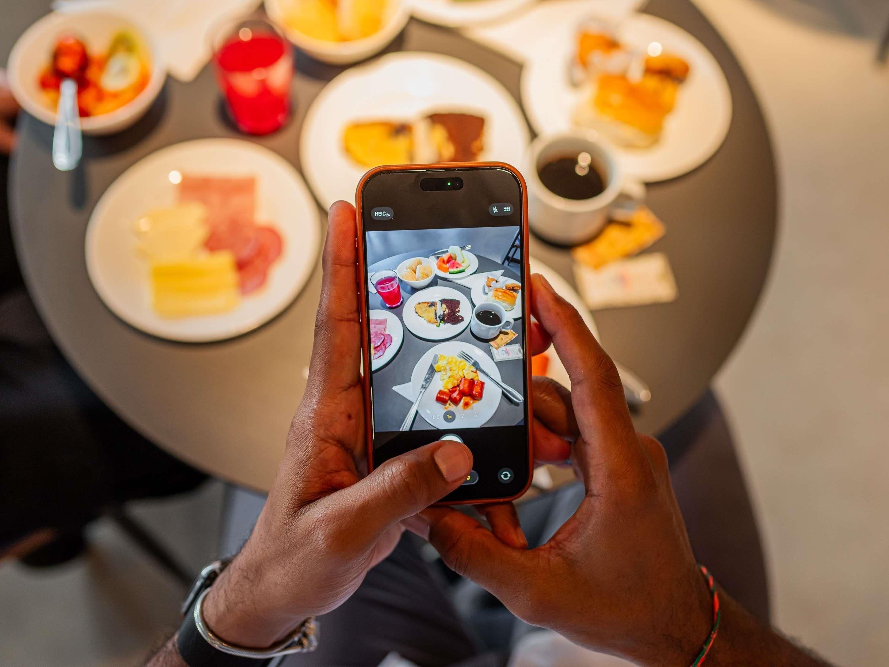 Iemand houdt een smartphone vast, waarop een foto van een maaltijd staat.