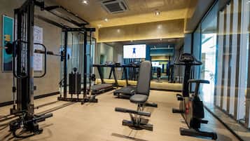 Un gimnasio con equipo de ejercicio, cinta de correr y banco para pesas.