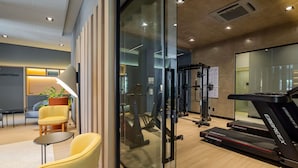 Un gimnasio moderno con equipo de ejercicio, una cinta de correr y una pared de vidrio.
