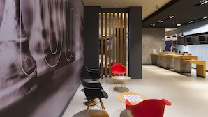 Un interior moderno con una recepción, zona de estar y un gran mural abstracto.