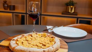 Une pizza garnie de tranches de banane, présentée sur une planche en bois, posée sur une table.