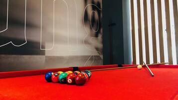 Una mesa de billar roja con bolas de billar frente a una pared con diseños abstractos.