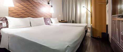 A hotel room with a large bed, two bedside tables, a desk, a chair, a TV, and a wardrobe.