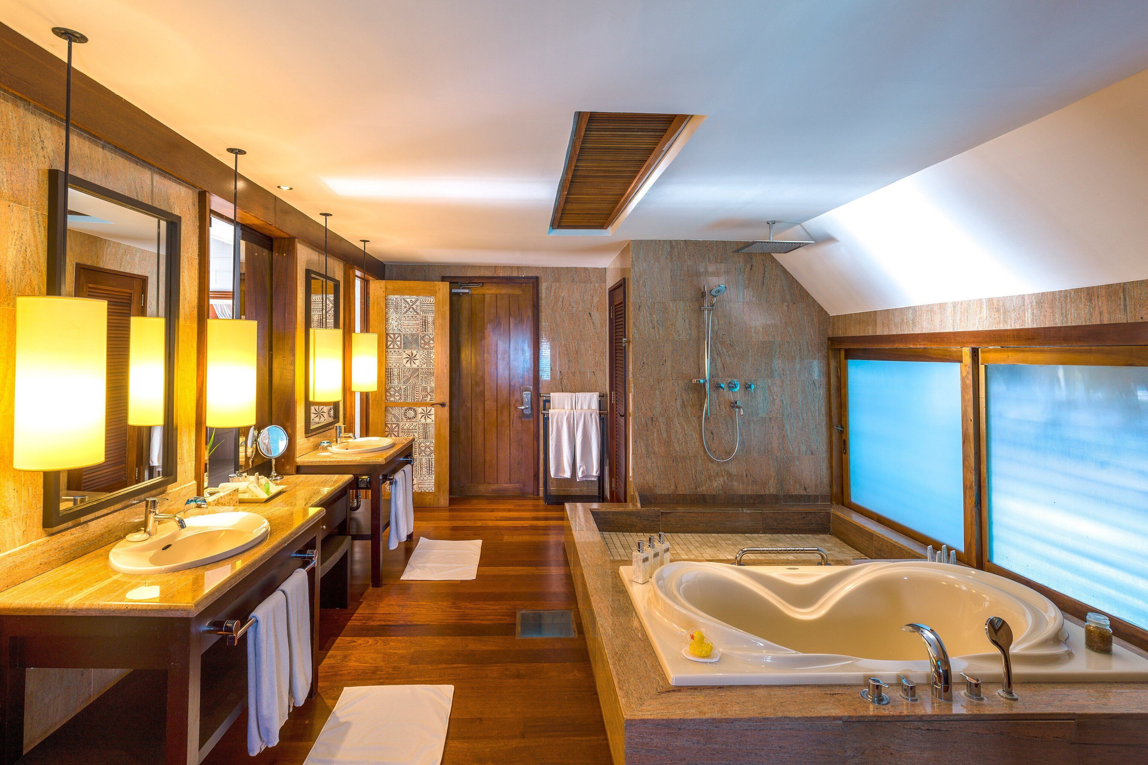 A modern bathroom with two sinks, a large bathtub, and a shower.
