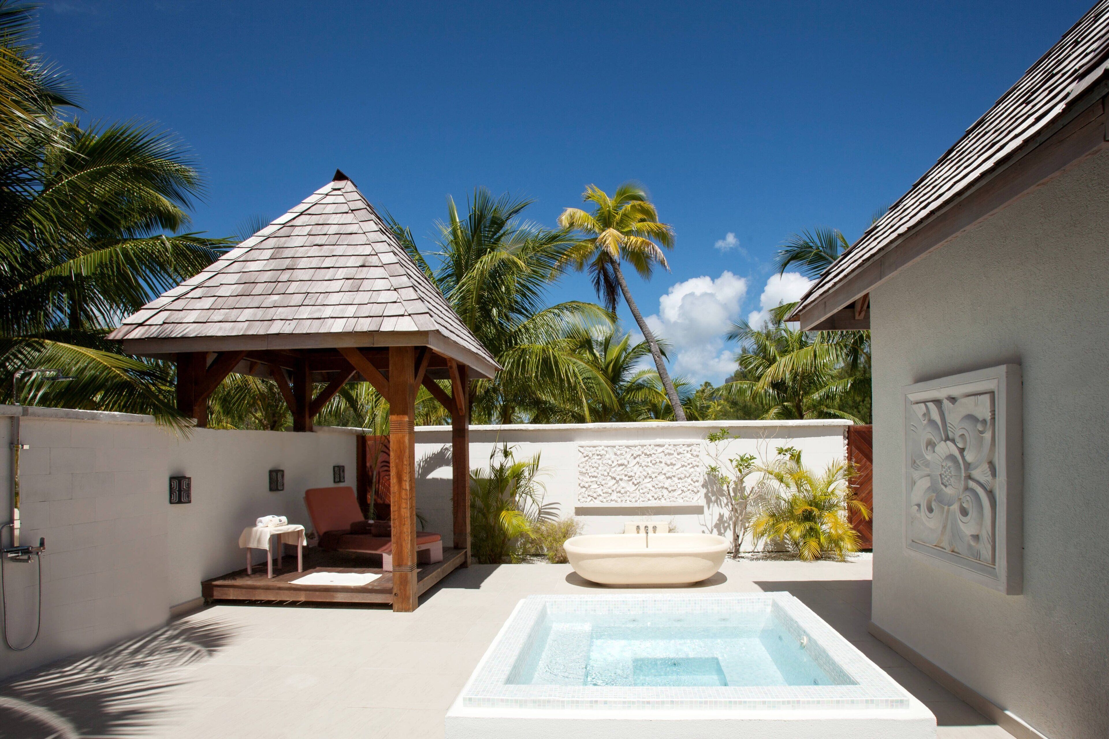 A private pool area with a hot tub, a gazebo, and a seating area with a table and chairs.