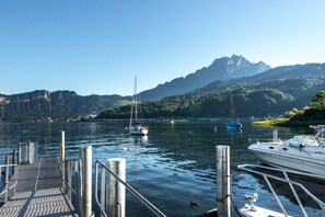A marina with boats docked, a dock extending into calm water, and mountains in the background. - Seehotel Sternen (Horw)