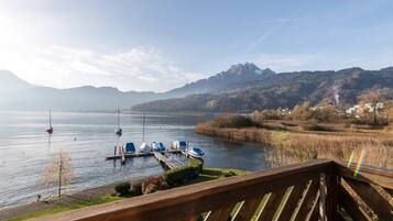 Une vue sur le lac, avec des bateaux amarrés, une terrasse en bois et des montagnes en arrière-plan.