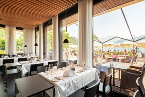 A restaurant with tables set for dining, large windows, and a view of the outdoors. - Seehotel Sternen (Horw)