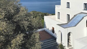 A modern white building with a view of the sea and distant mountains. - Relais Regina Giovanna (Sorrento)