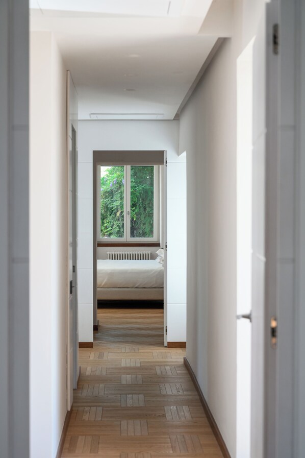 A narrow hallway leading to a bedroom with a window, a radiator, and a bed. - Relais Regina Giovanna (Sorrento)