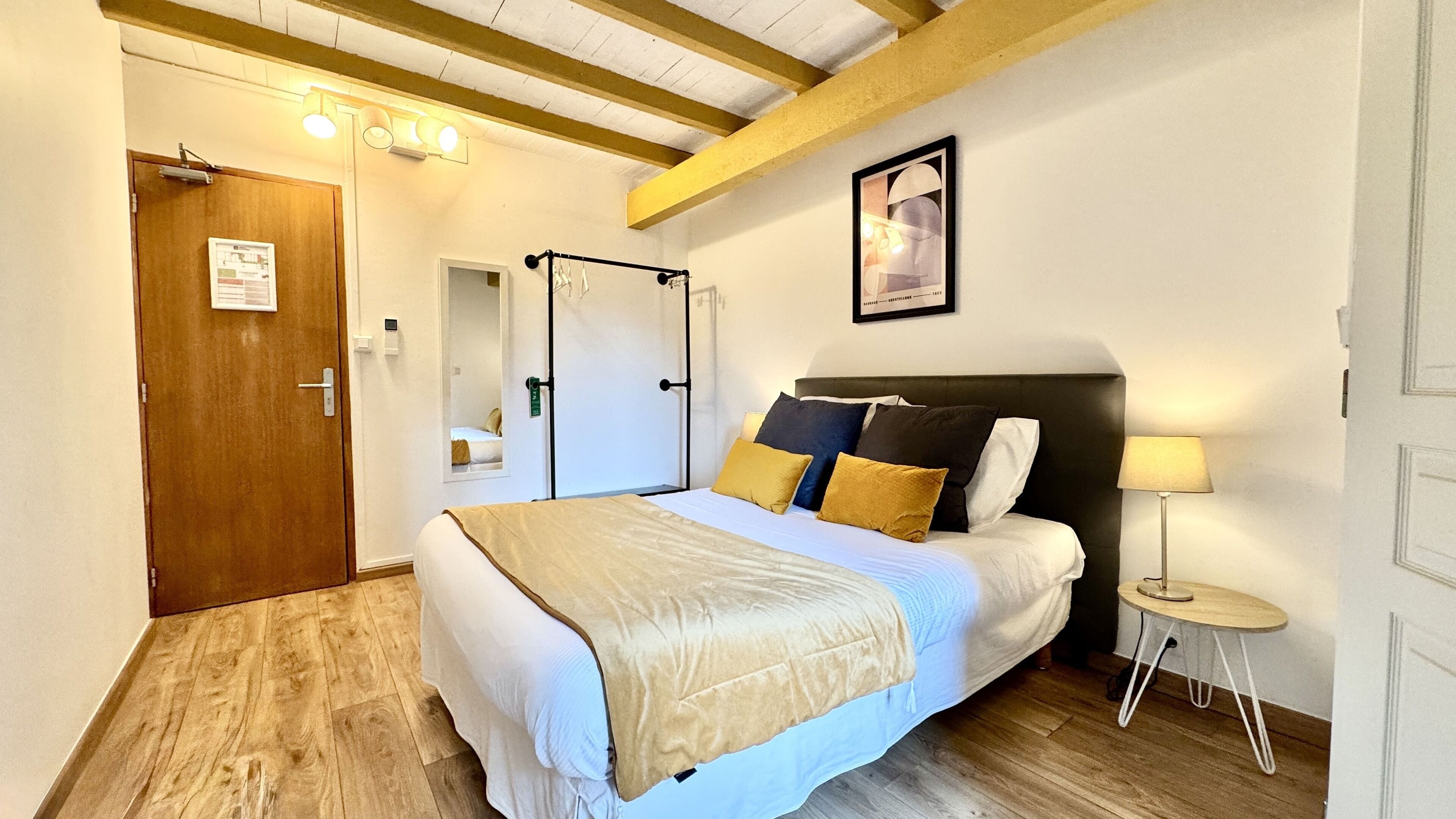 A bedroom with a bed, bedside table, and a mirror.