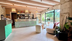 Zona de bar con barra, taburetes y un área de estar con una mesa redonda y sillas.