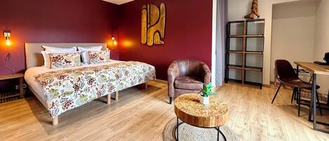 A bedroom with a bed, a chair, a round wooden table, and a bookshelf.