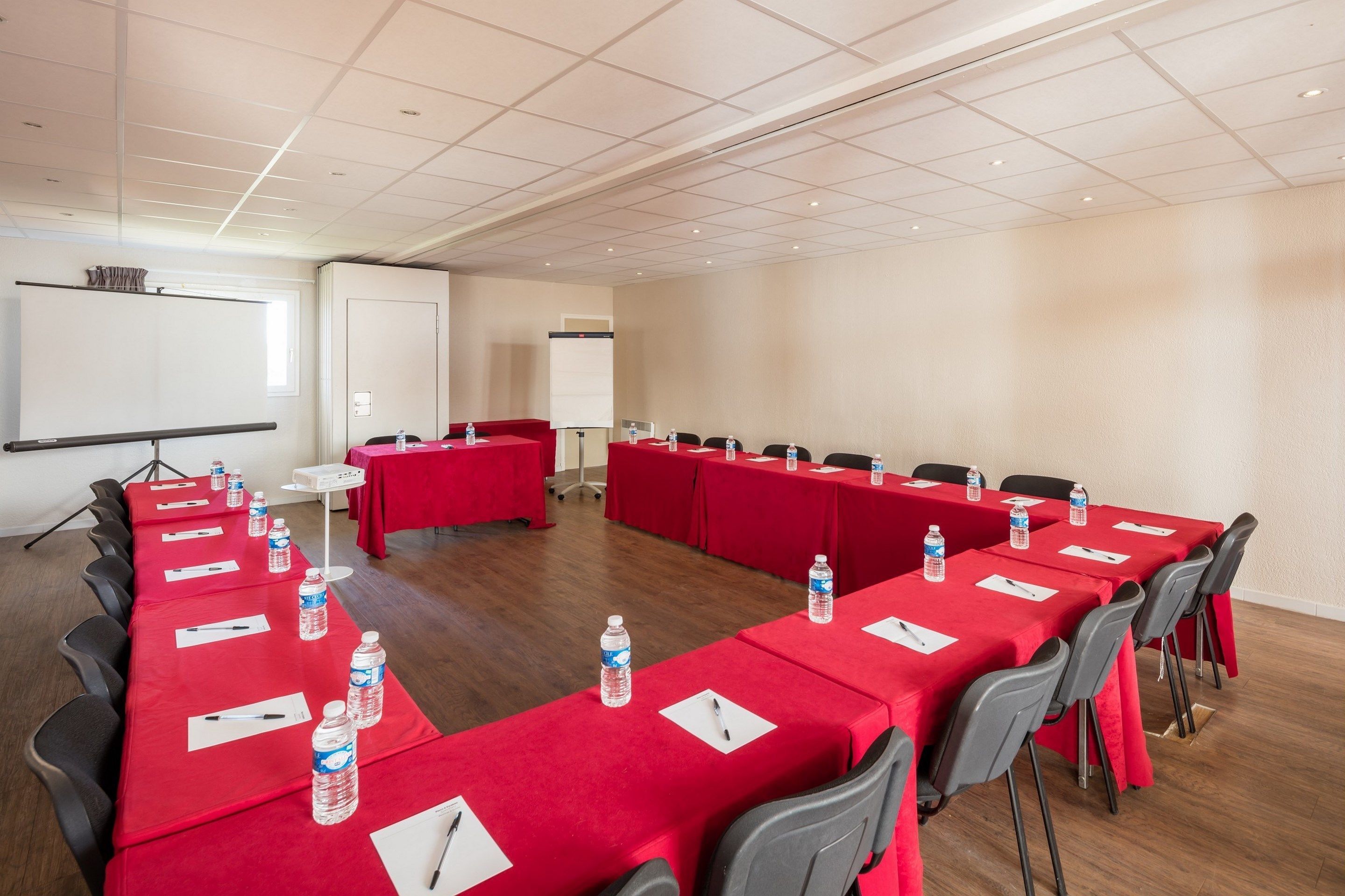 A conference room with long tables, chairs, and a whiteboard.