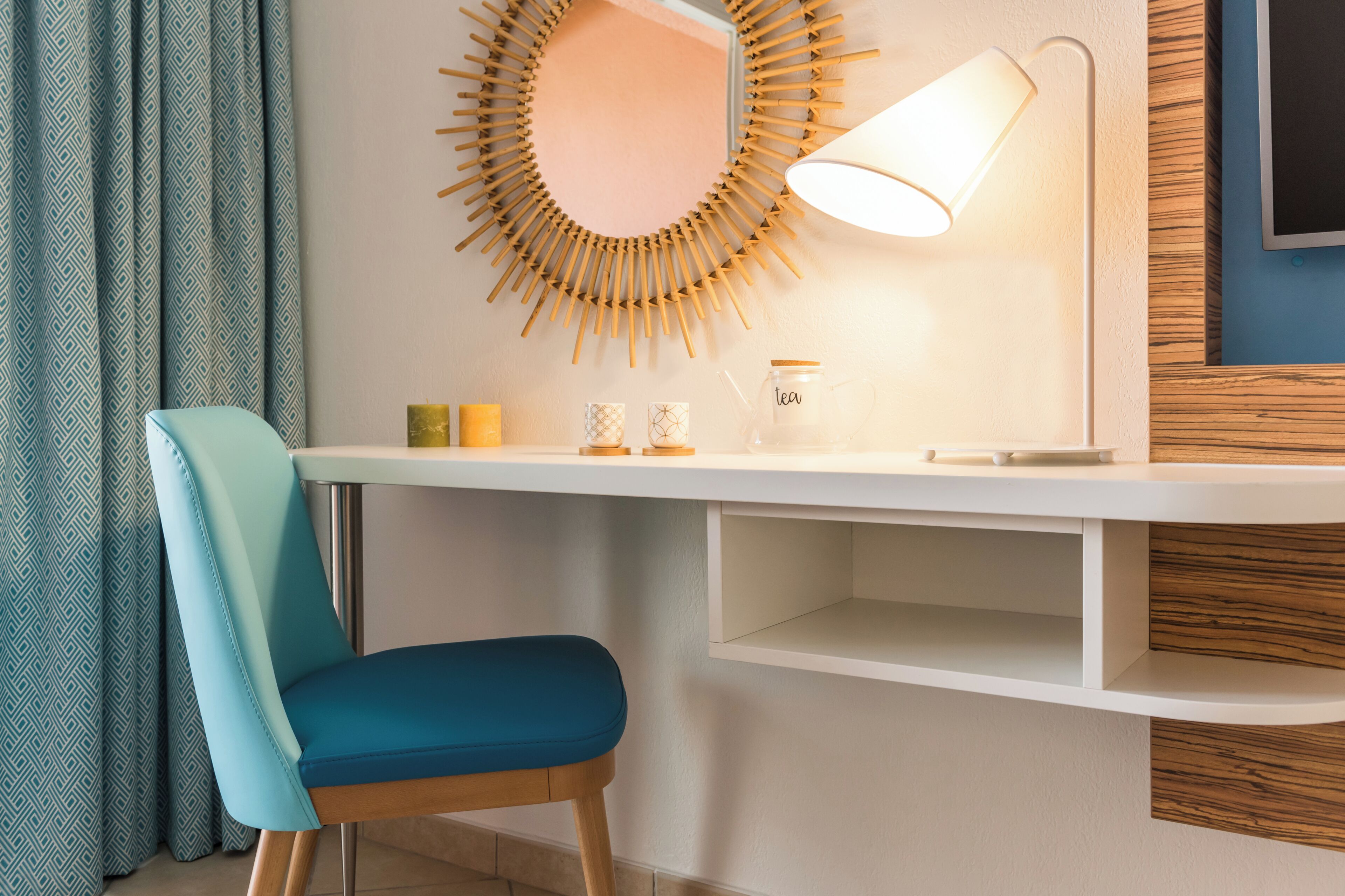 Una habitación moderna con escritorio, silla, lámpara de pared y espejo.