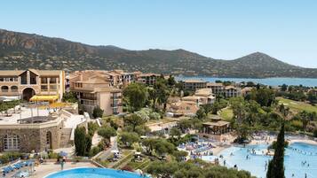 A resort with a large central pool, multiple smaller pools, and a view of the surrounding landscape.