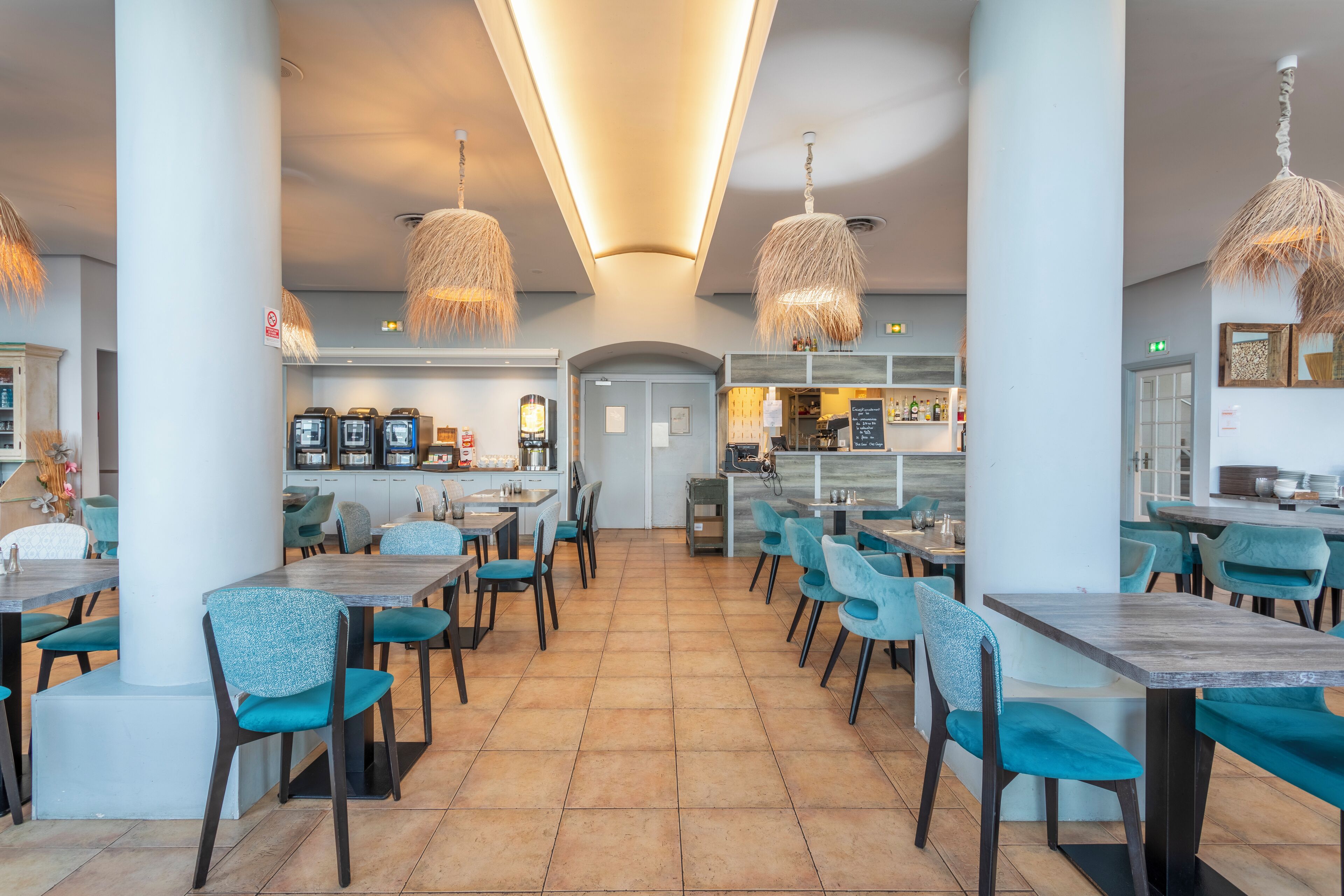 Un restaurante amplio con techos altos, iluminación moderna y una distribución limpia y ordenada.