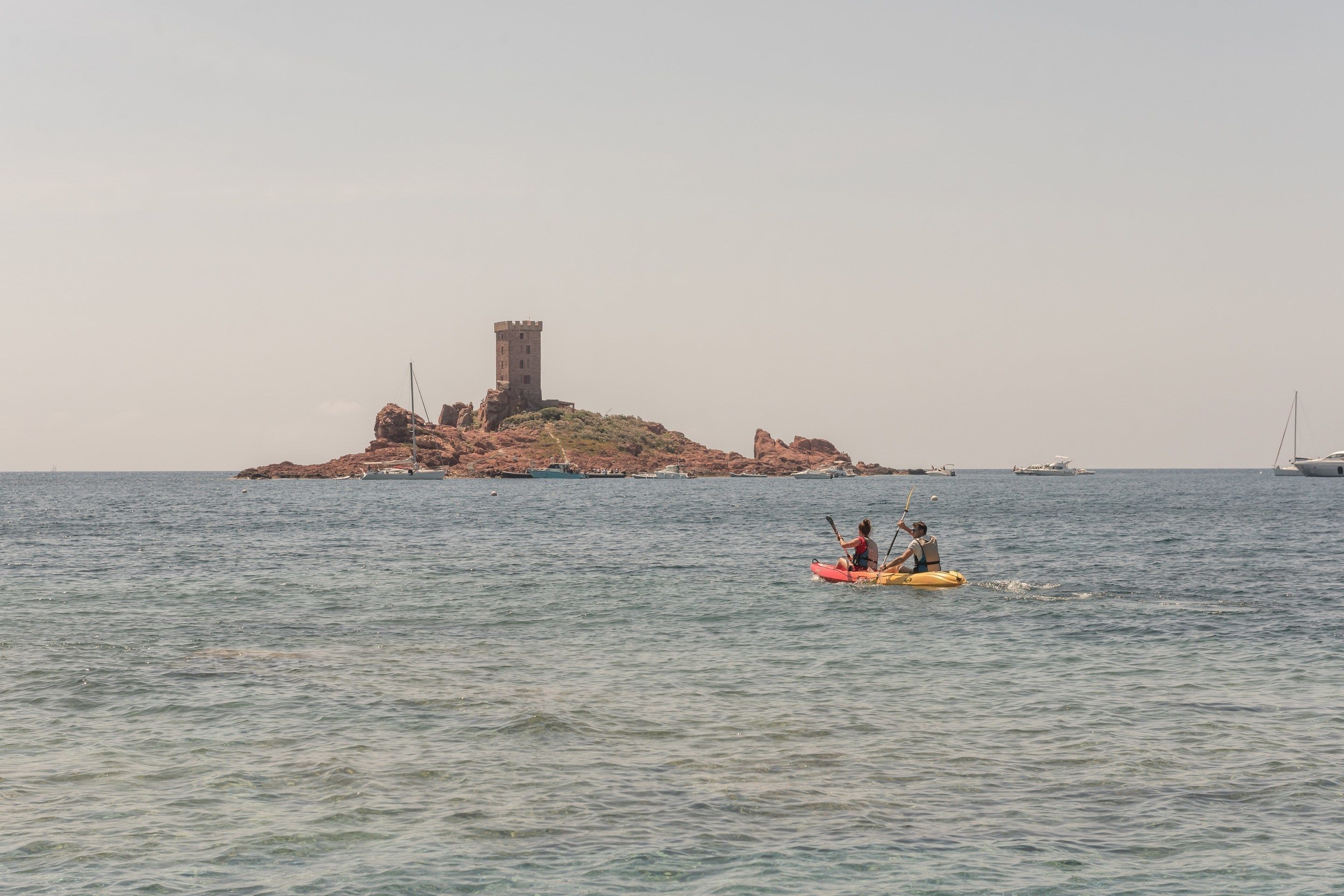 A calm sea with a small island featuring a tower.