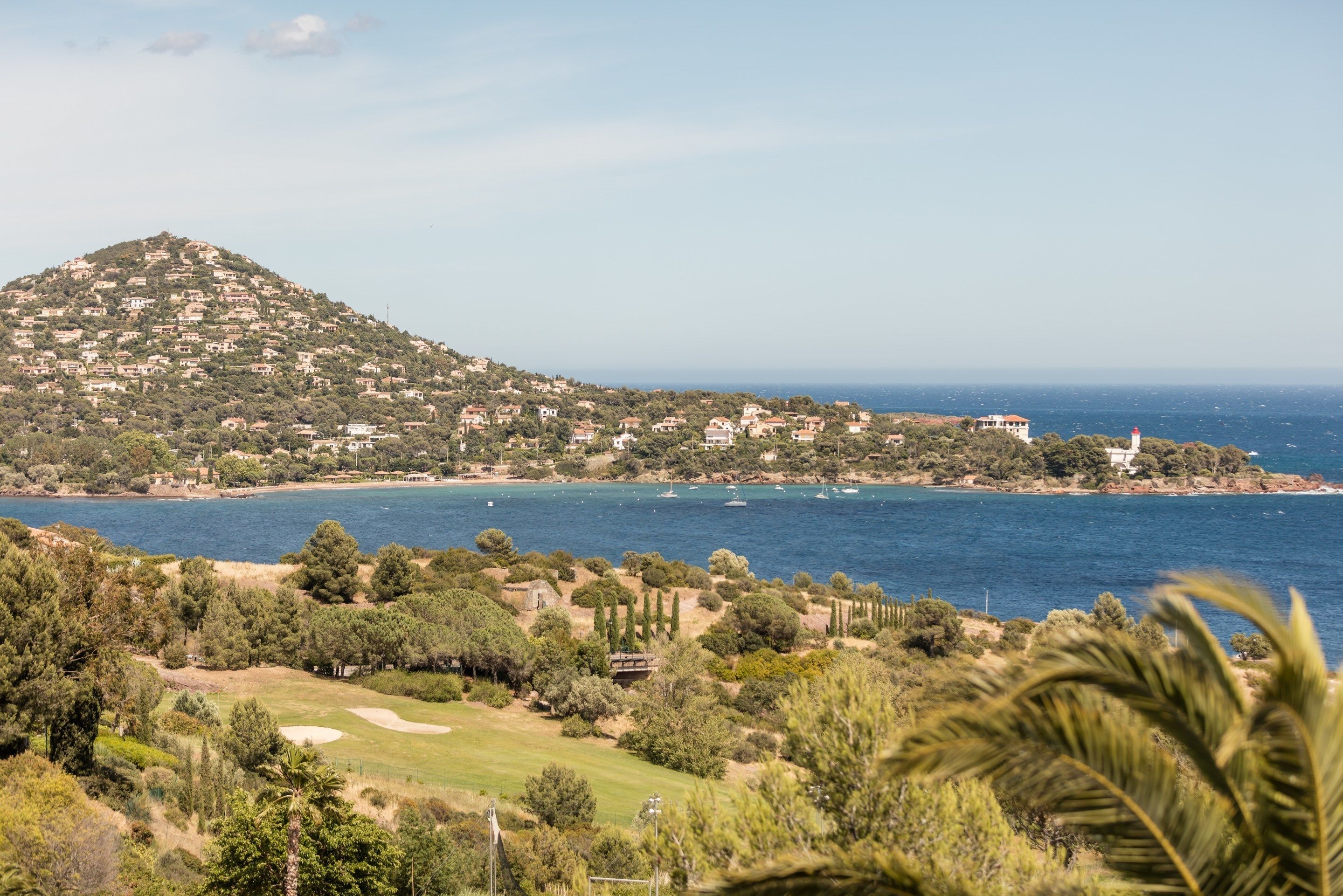 A coastal landscape with a hill, beach, and ocean.