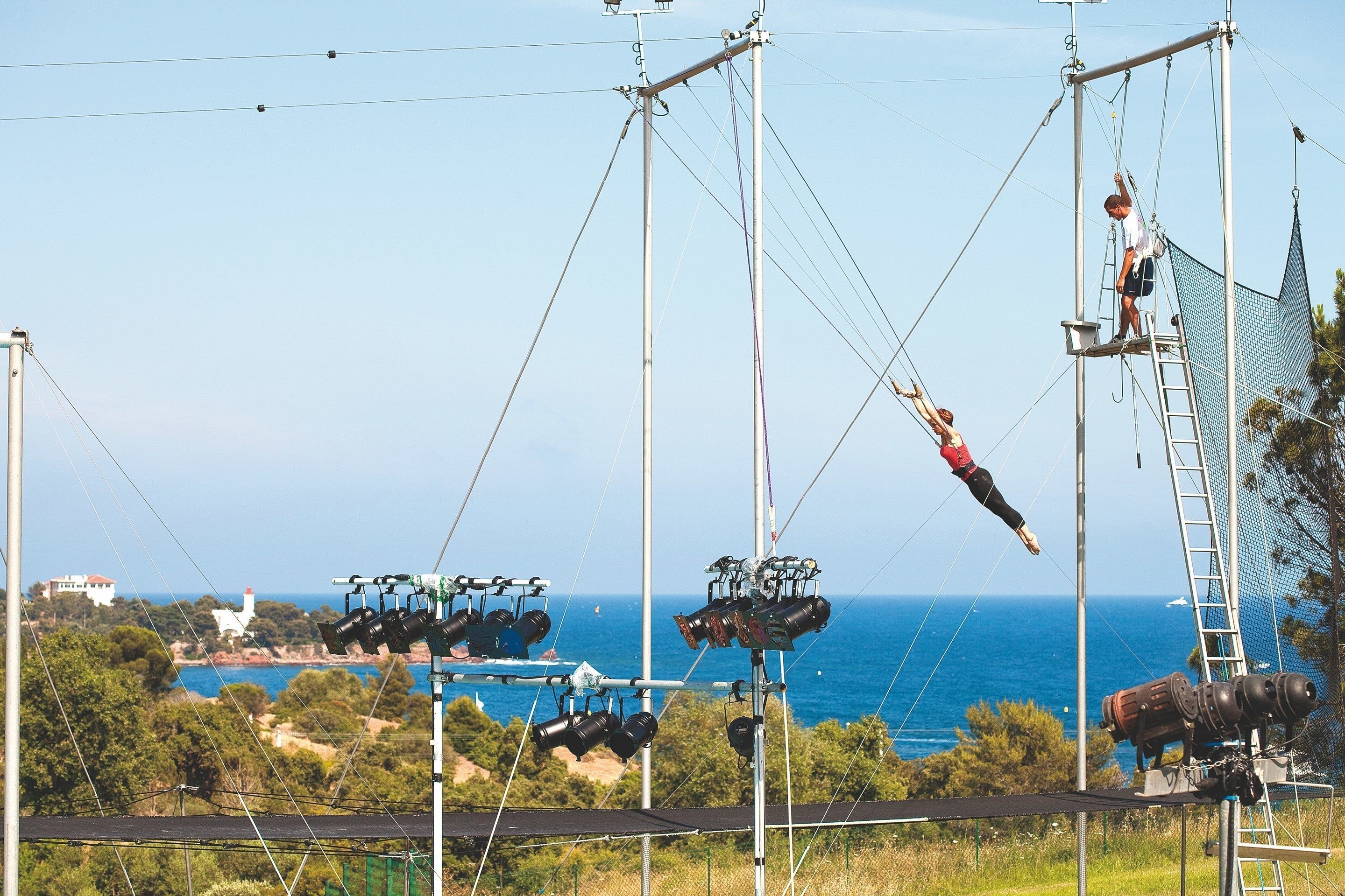 A cable car system with a view of the sea and buildings in the background.