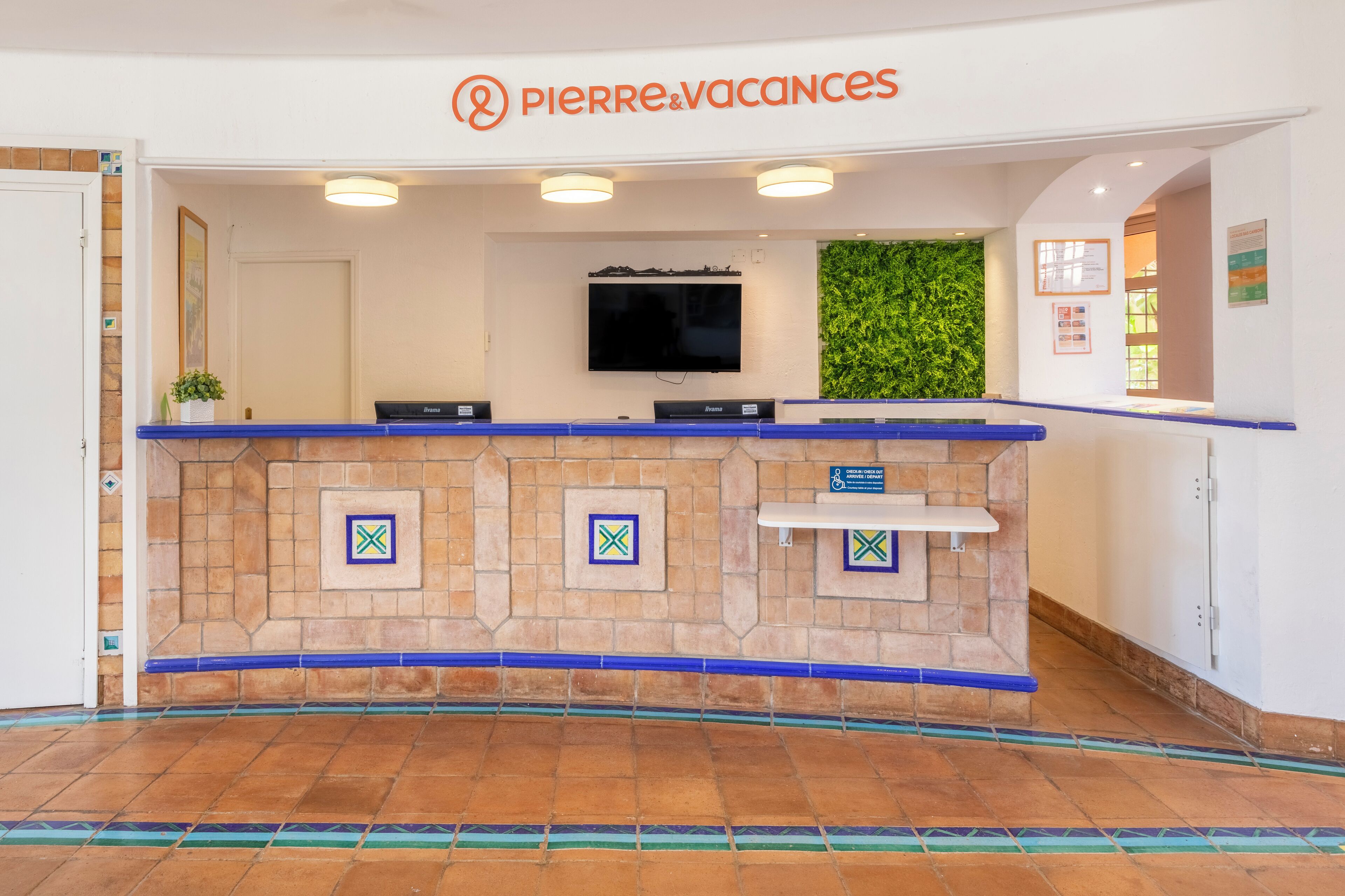 A reception area with a stone counter, a flat-screen TV, and a green wall.