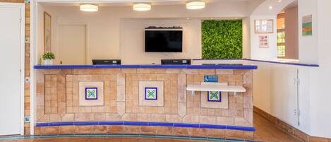 A reception area with a stone counter, a flat-screen TV, and a green wall.