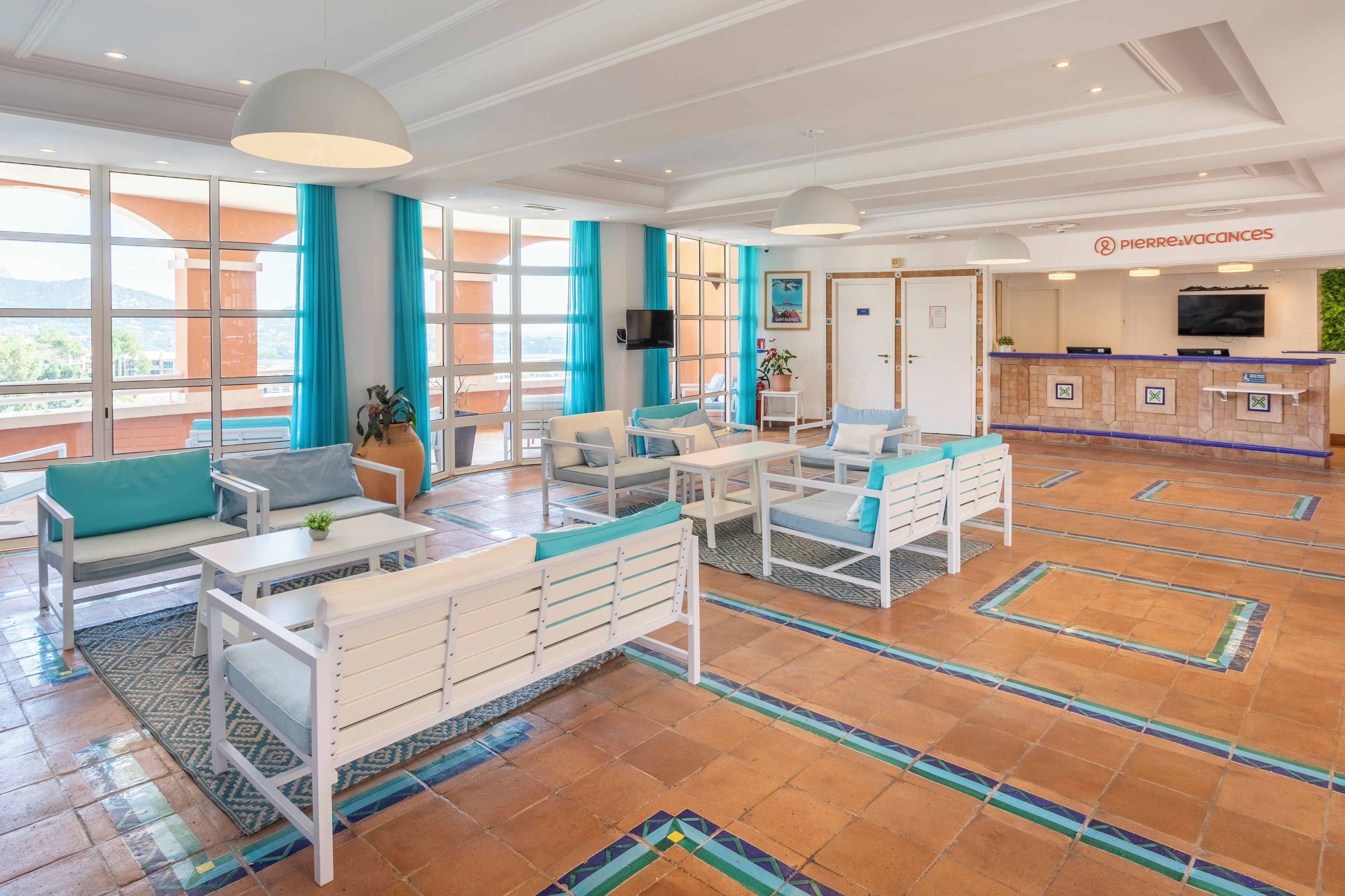 Un hall espacioso con mostrador de recepción, zona de estar y ventanas amplias con vistas al exterior.