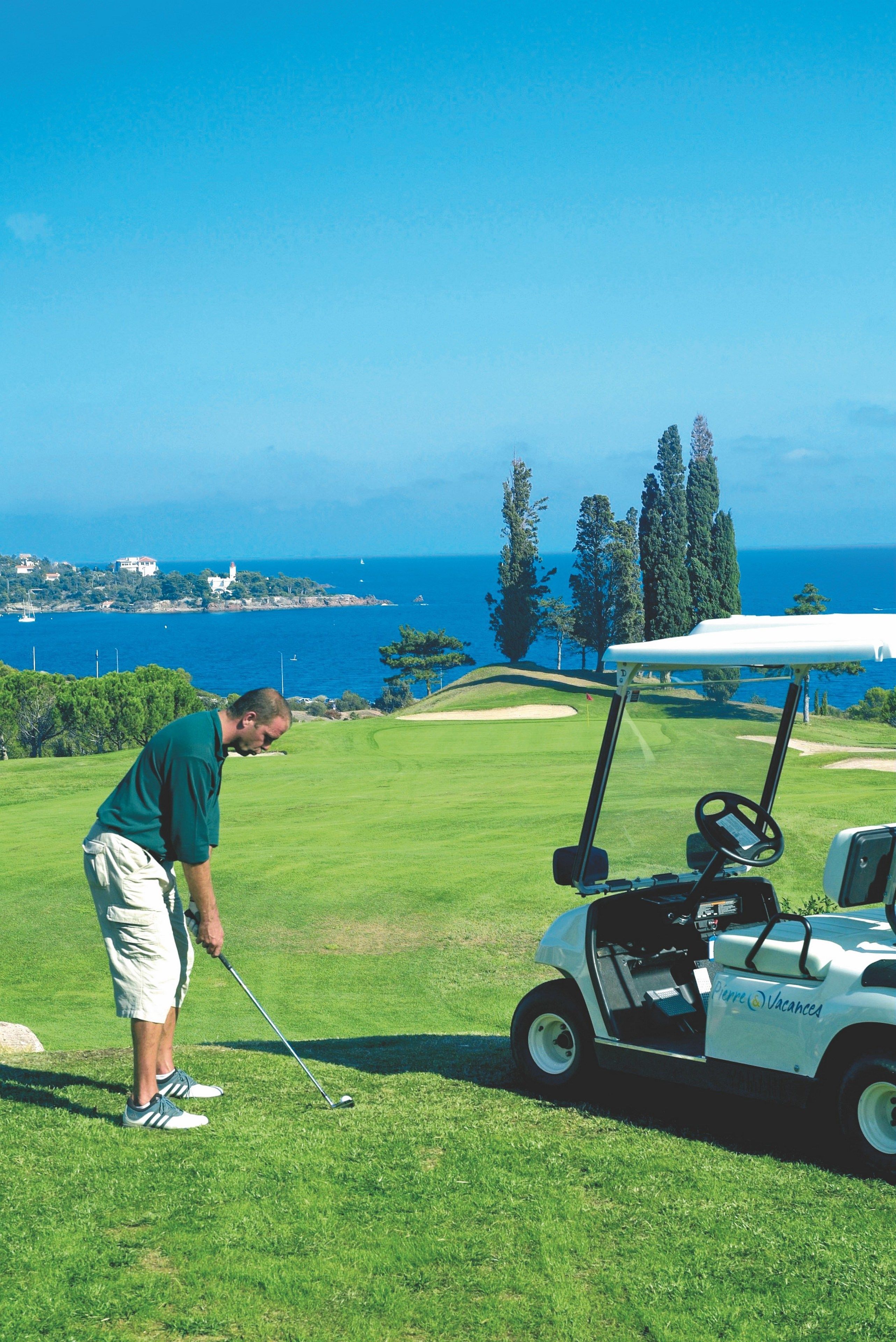 A golf course with a view of the ocean and trees in the background.