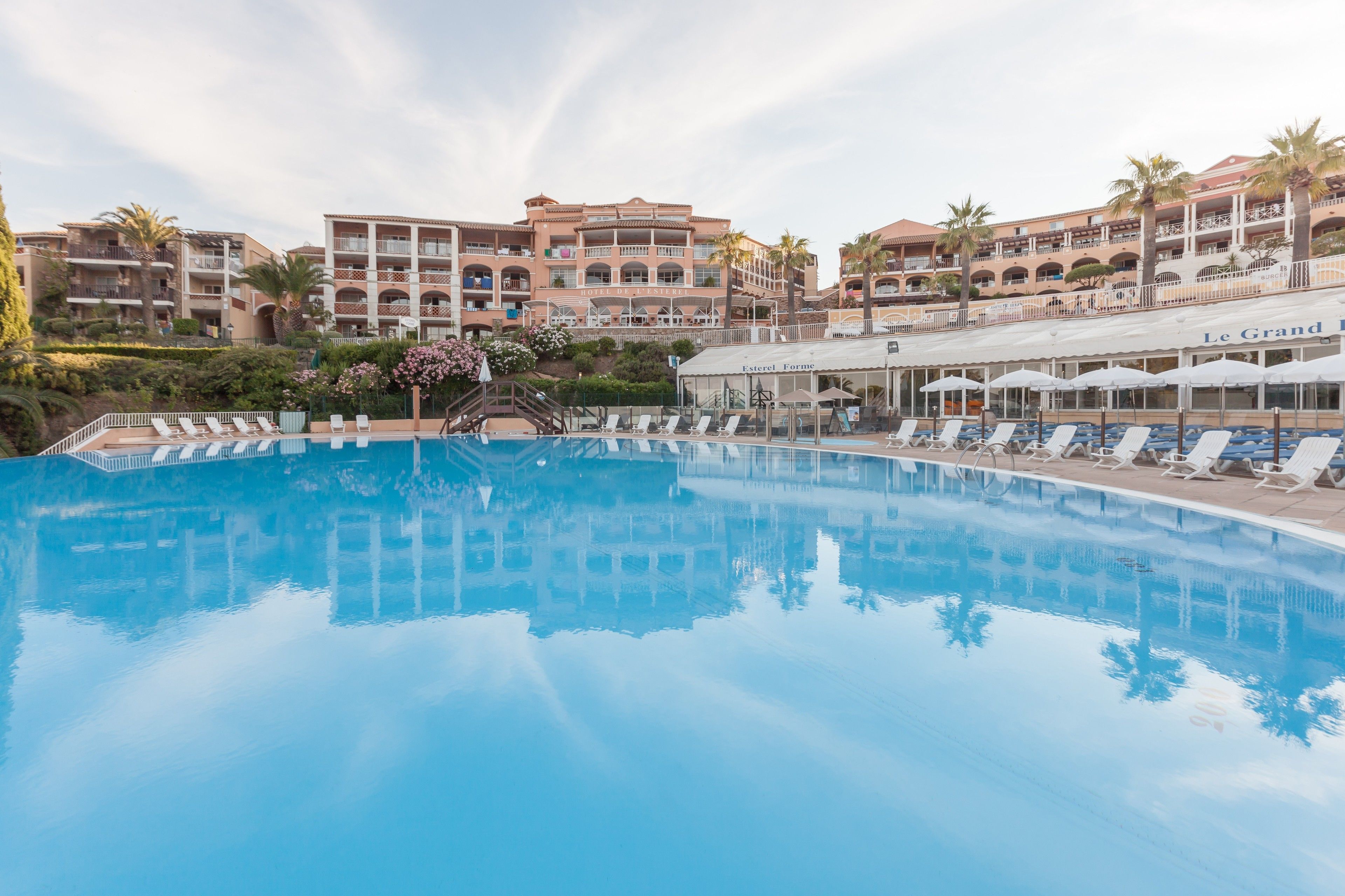 A large swimming pool with lounge chairs and a building with multiple balconies in the background.
