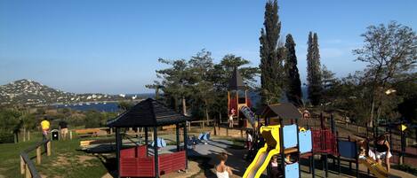 A playground with a slide, benches, and a gazebo.