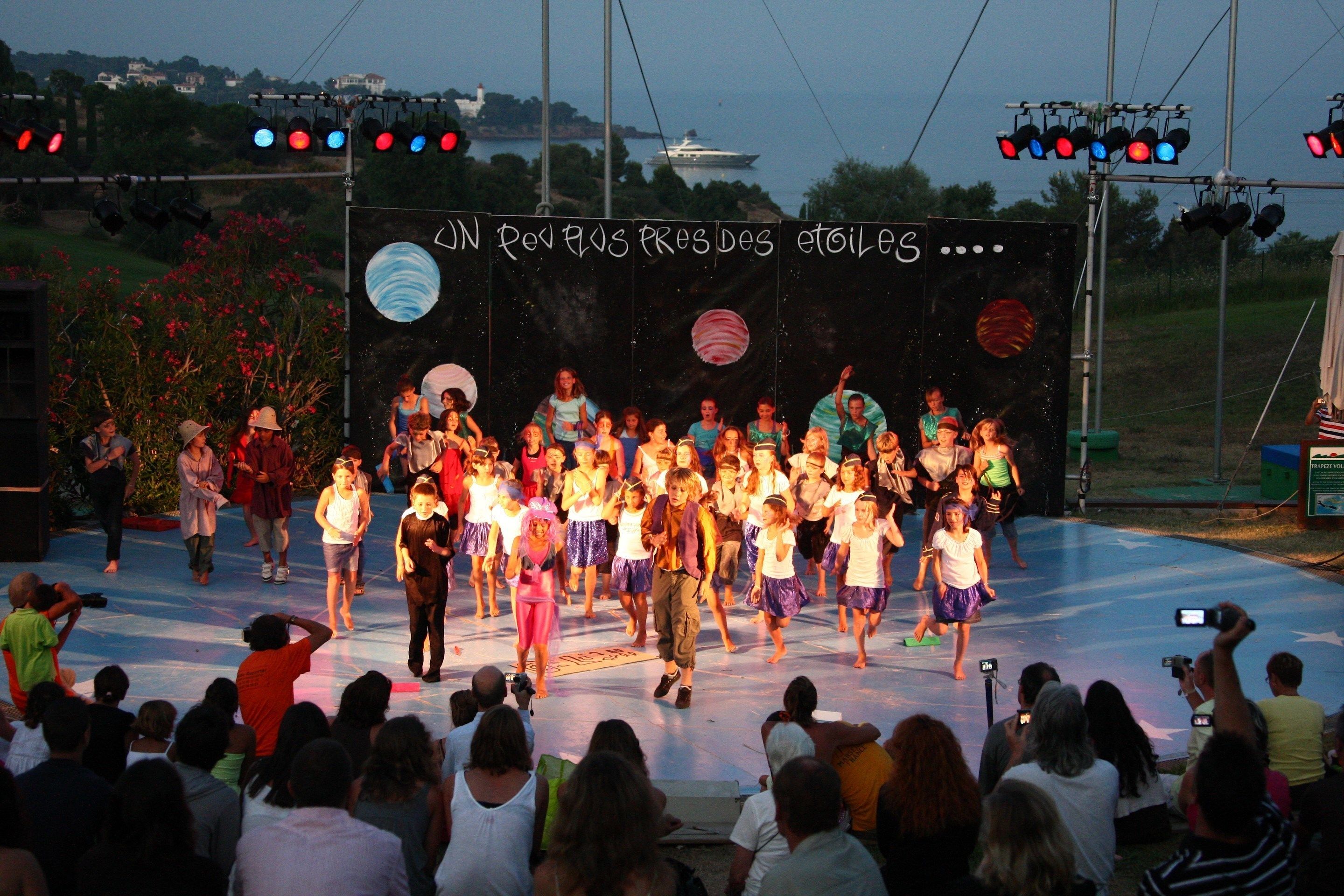 A stage with a group of people performing, surrounded by an audience.