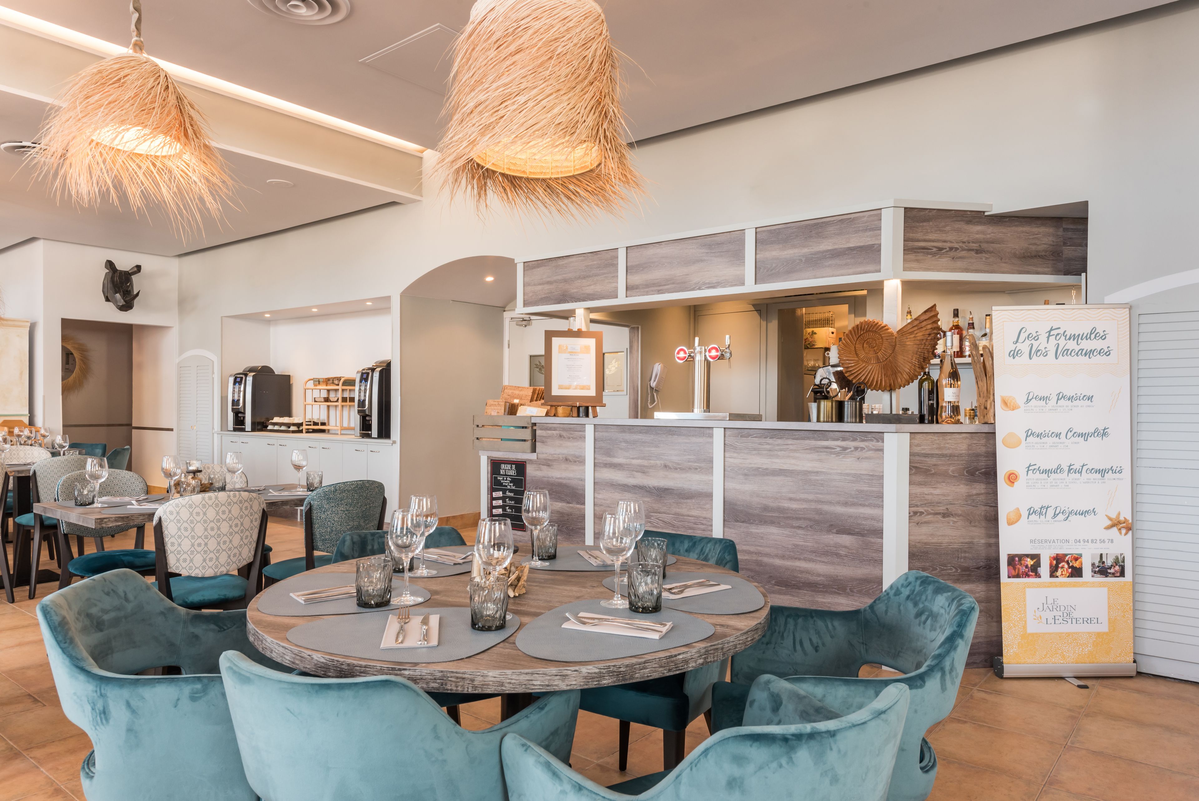 Un restaurant moderne avec des tables rondes, des chaises de couleur turquoise et un bar en bois.